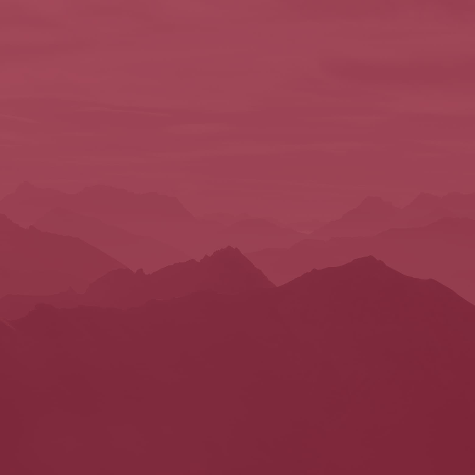Silhouetted mountain range in shades of red, creating a layered and atmospheric landscape effect.
